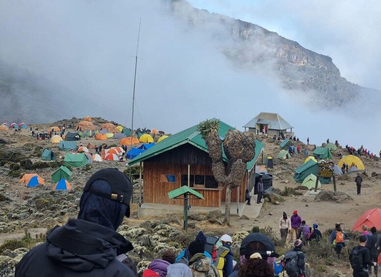 A mountainous campsite with tents and a wooden cabin. 5