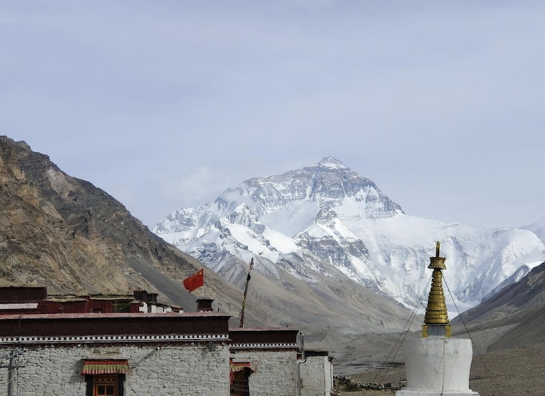 A mountain with a snow-capped peak, a flag, a building with a red roof, and a golden stupa. 1