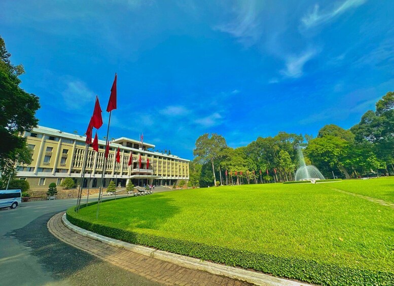 Un edificio con varias banderas rojas, una fuente y un césped bien cuidado. 1
