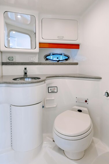 A compact bathroom with a white toilet, a sink with a faucet, and a mirror. 2