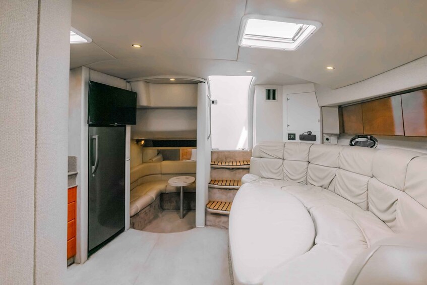 A compact RV interior with a sofa, a small table, a TV, and a refrigerator. 3
