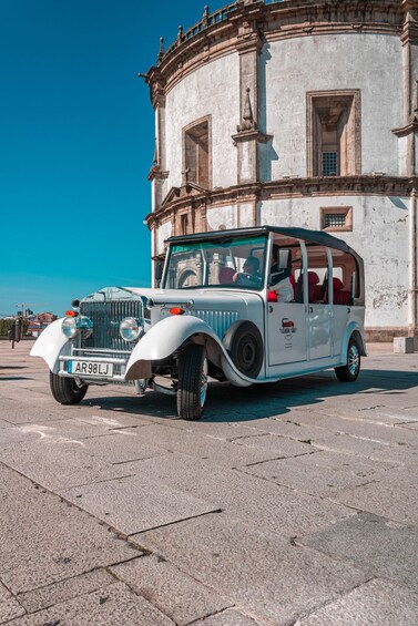 A vintage white car parked in front of a historic building. 2
