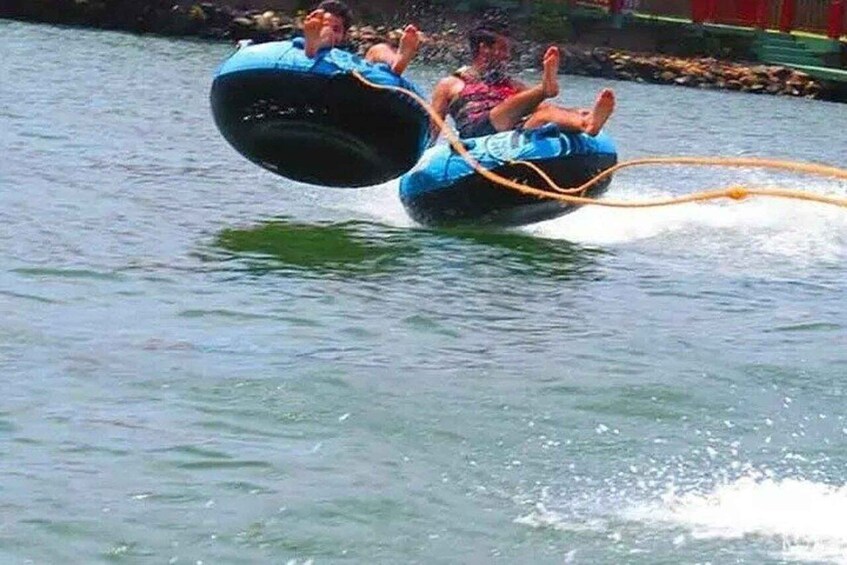 Two people in blue tubes being pulled by a rope on a body of water. 3