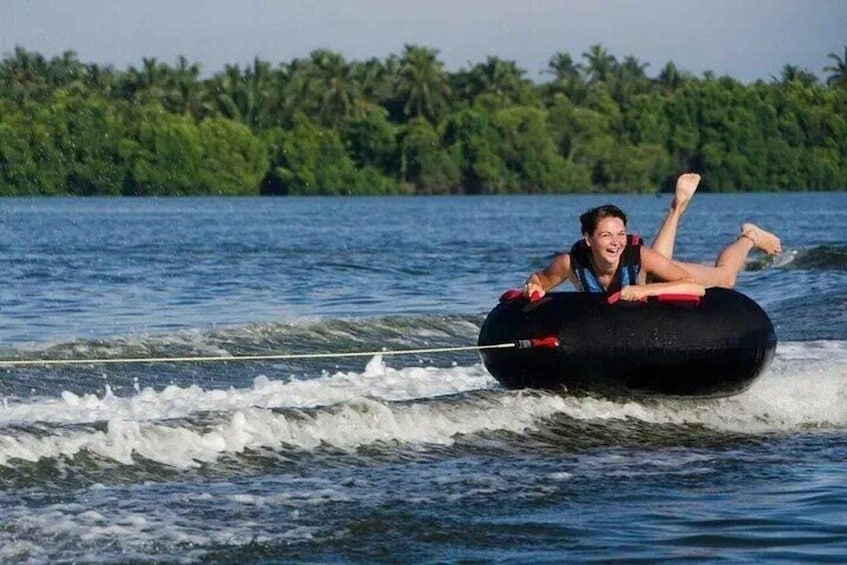 A person water skiing on a black tube with a rope. 2