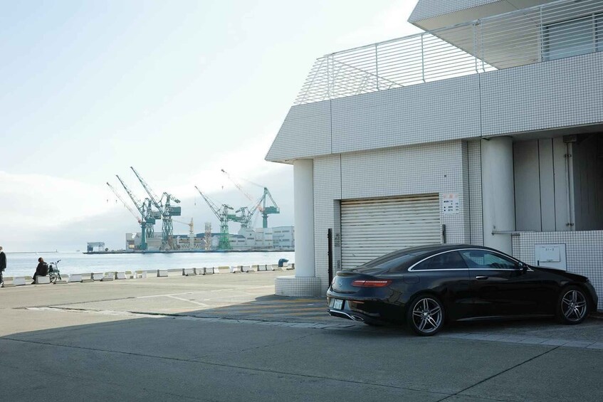 A black car parked in front of a modern building with a tiled facade. 2