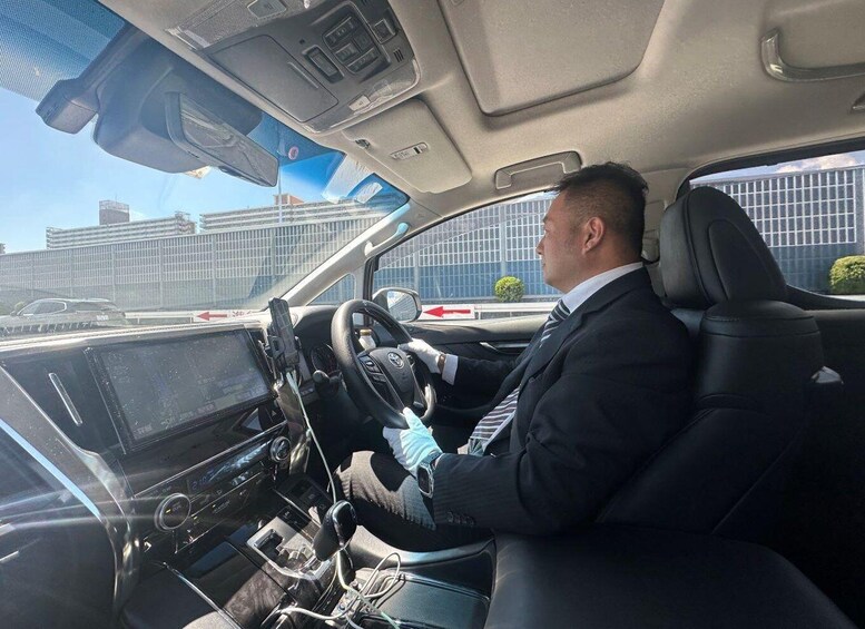 A man driving a car with a steering wheel, dashboard, and gear shift. 3