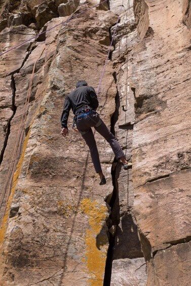 A person climbing a rock face with a rope. 3