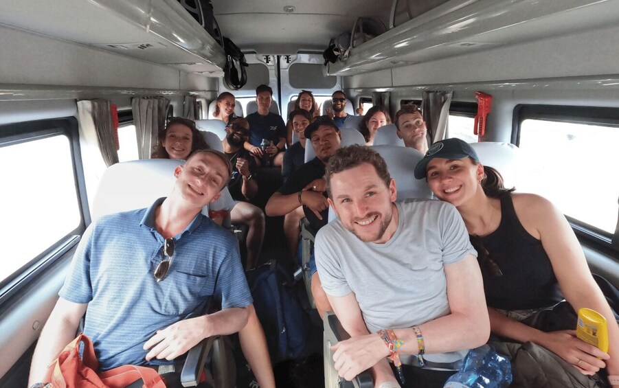 A group of people seated inside a vehicle, likely a bus or train, with windows on the side. 2