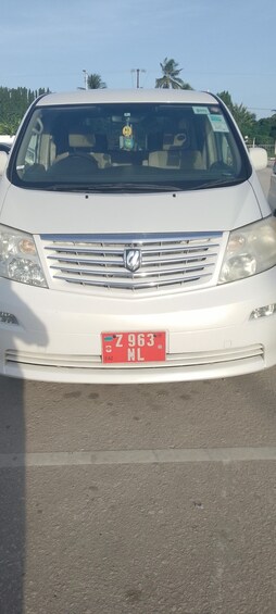 A white car with a red license plate in a parking lot. 1