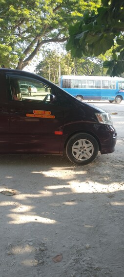 A dark-colored van parked on a dirt road with a sign indicating it is for private hire. 5