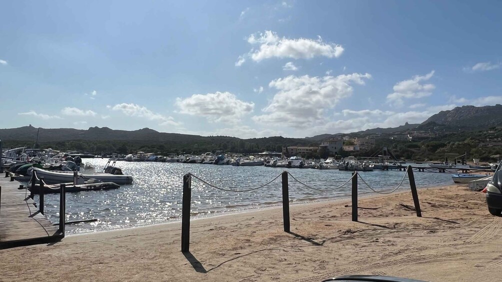 A marina with boats docked, a sandy beach, and mountains in the background. 4
