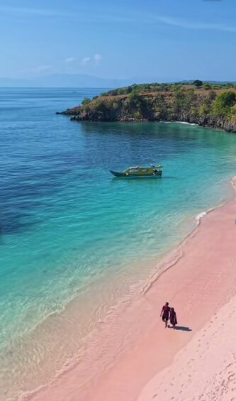 A beach with clear turquoise water, a small boat, and a person walking along the shore. 4