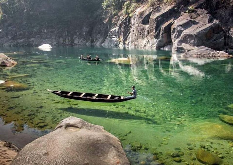 A clear river with rocks and a boat with people. 1