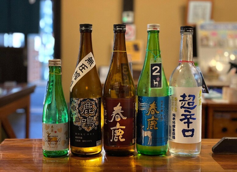 Five bottles of Japanese sake on a wooden table. 2