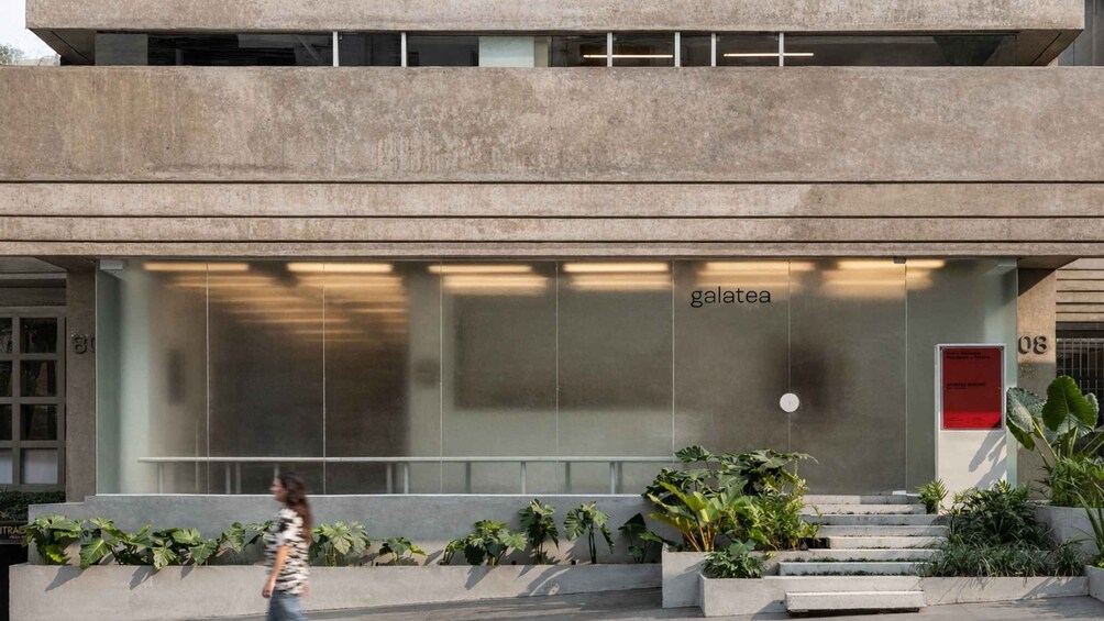 A modern building with a large glass facade, a red door, and a sign that reads 'galatea'. 2