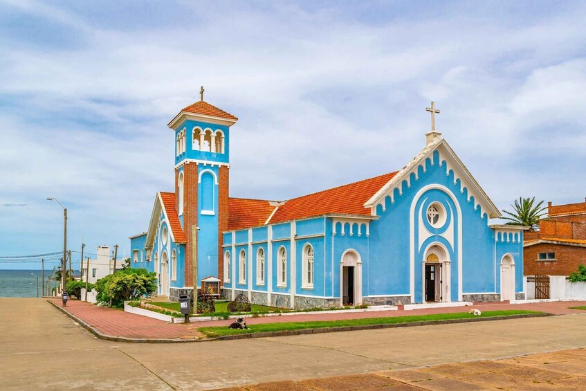 A blue church with a bell tower and a cross on top. 1