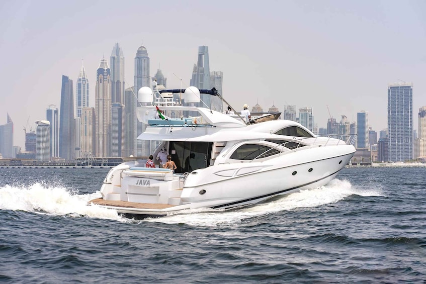 A white yacht named "JAVA" cruising on water with a city skyline in the background. 5