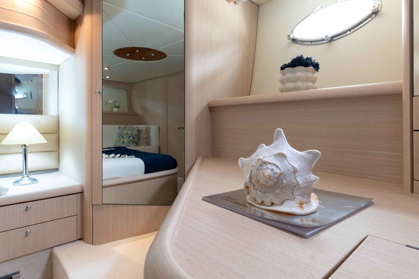 A modern interior with a curved wooden countertop, a decorative shell, a bedside lamp, and a mirror reflecting a bedroom. 5