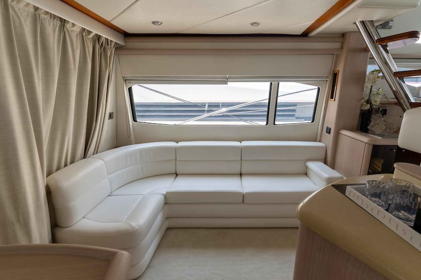 A modern interior with a white leather sofa, a large window with a view of the sea, and a small table with glasses. 3