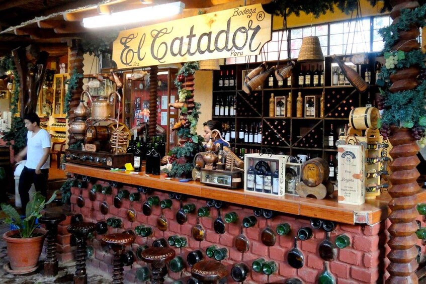 A bar named El Catador in Peru, featuring a brick wall with wine bottles, shelves with bottles, and a signboard. 5