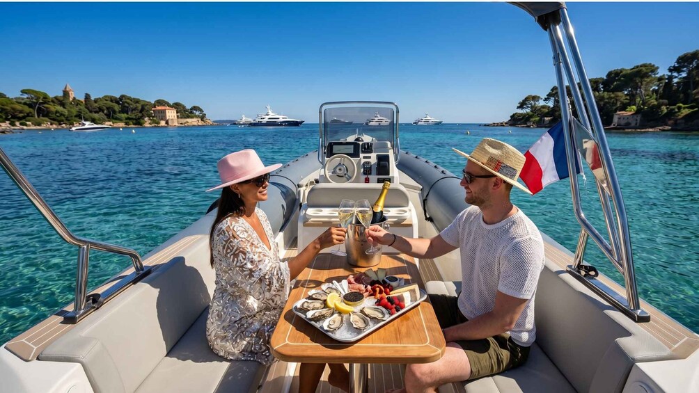 A couple on a boat with a table of food and drinks, surrounded by clear water and distant boats. 1
