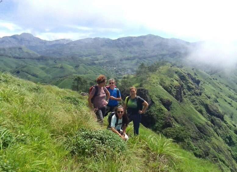 A group of hikers on a grassy hillside with a mountainous landscape in the background. 3