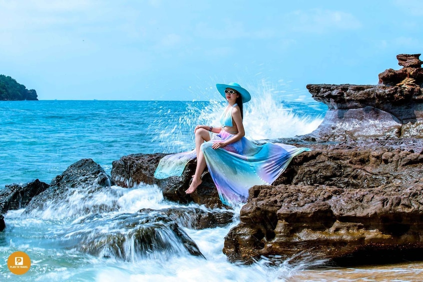 A person sitting on rocks by the ocean with waves crashing around them. 5