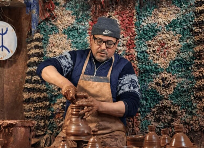 A person shaping clay pots in a workshop with a colorful, patterned background. 4