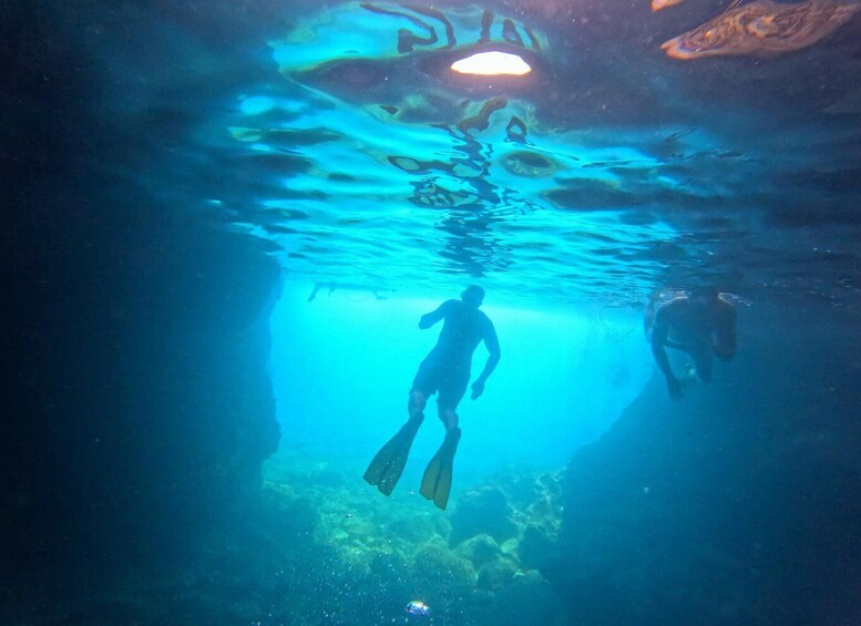 A diver underwater in a cave with another diver in the background. 4