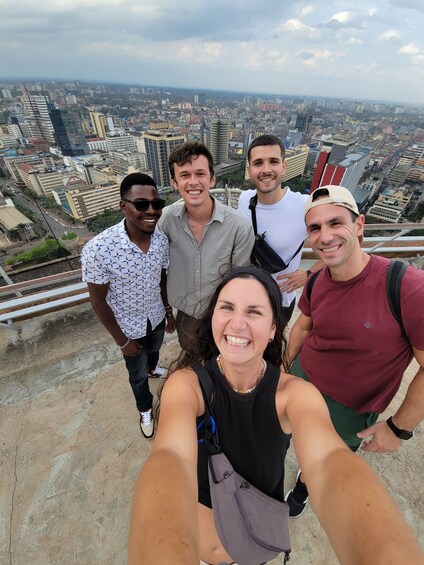 A group of people taking a selfie on a high vantage point overlooking a cityscape. 1