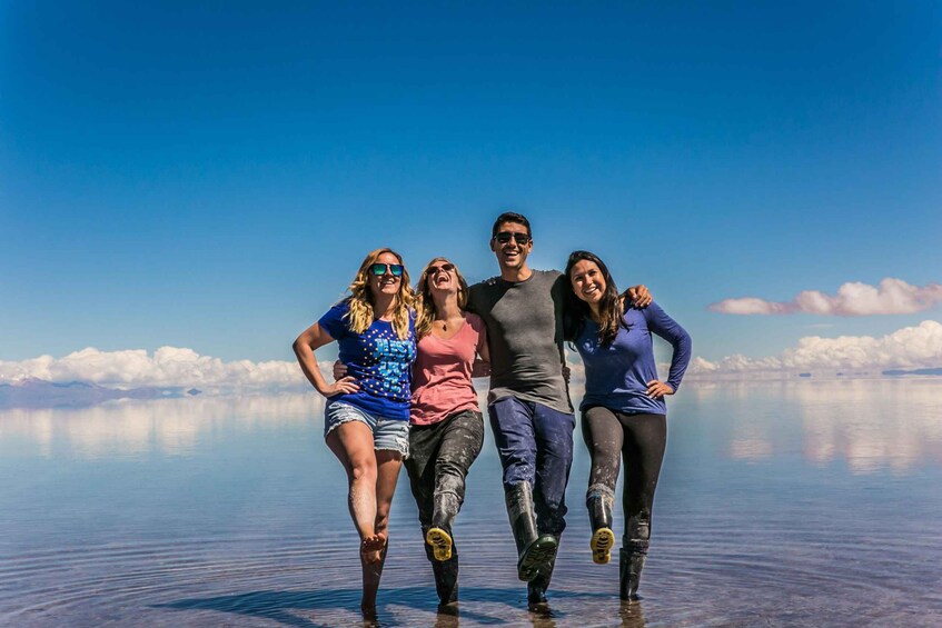 Four people running on a reflective water surface with a clear sky and mountains in the background. 5