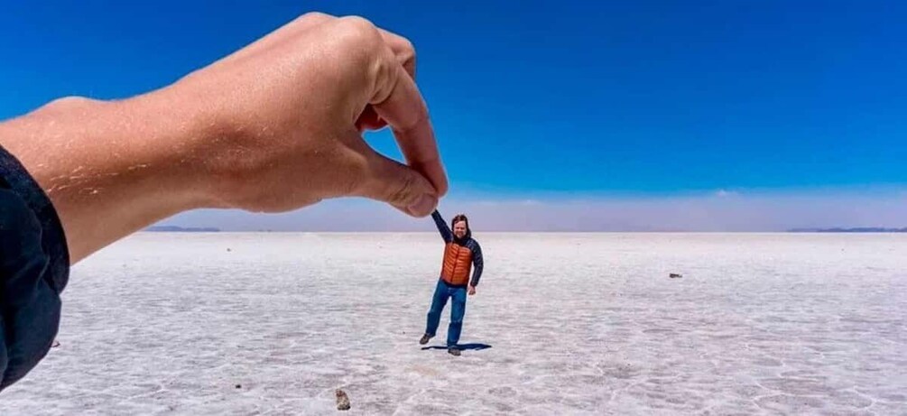 A person in a desert with a large hand pointing at them. 3