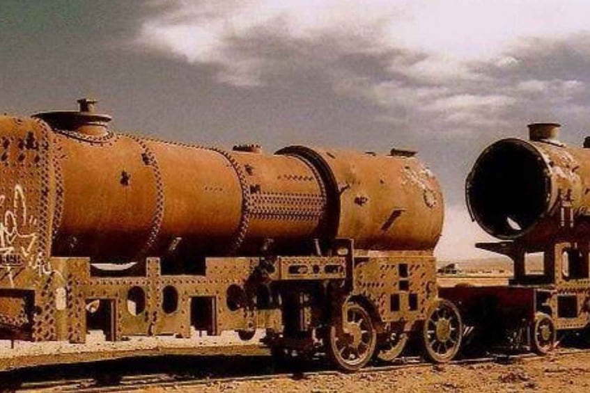 A rusted, abandoned train with large cylindrical tanks and intricate metalwork. 2