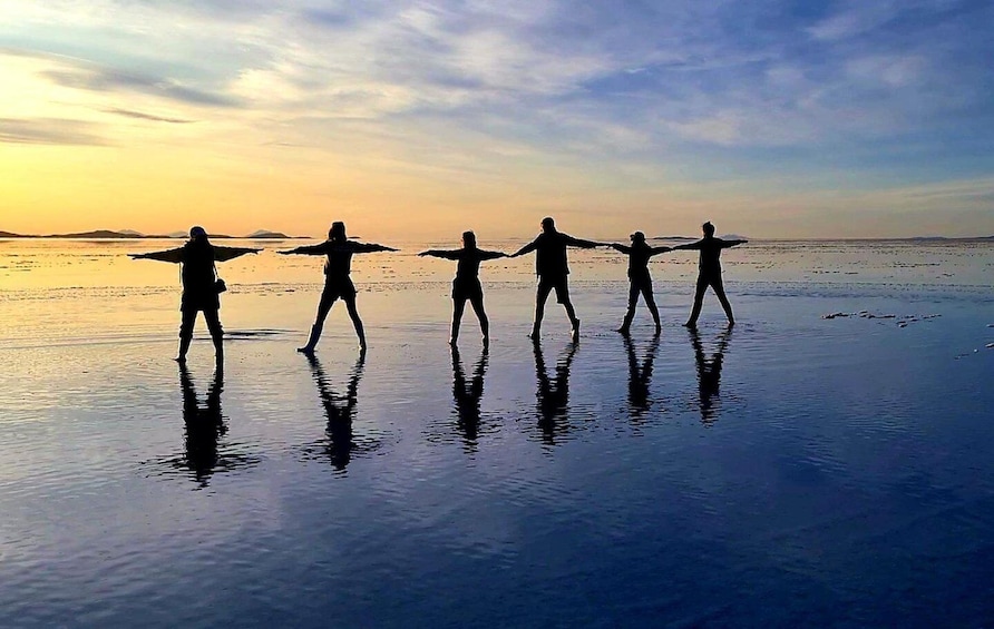 Silhouettes of people performing a synchronized dance on a beach at sunset. 1