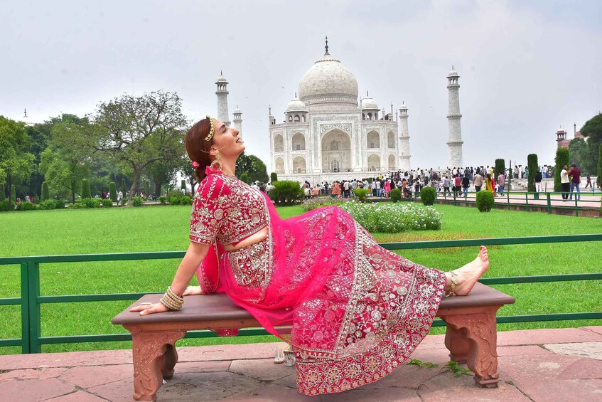 A woman in traditional attire sitting on a bench with the Taj Mahal in the background. 3
