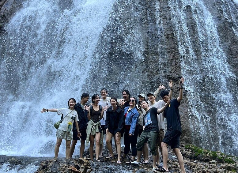 A group of people standing in front of a waterfall. 3
