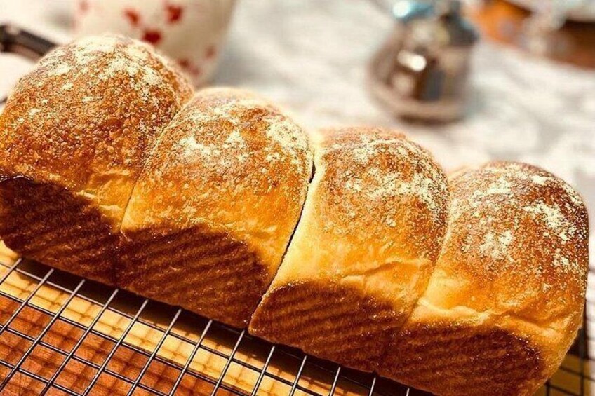 A loaf of bread with a dusting of flour on a wire cooling rack. 2