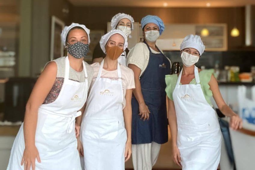 Cuatro personas en una cocina, usando delantales y cofias. 2