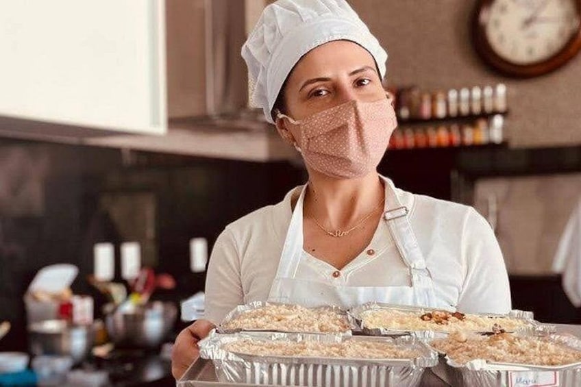 Una persona con uniforme de chef sostiene bandejas de comida. 3