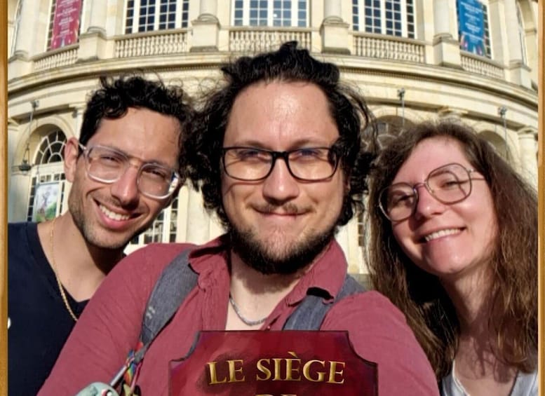 Three people in front of a building with a sign reading 'LE SIÈGE.' 2
