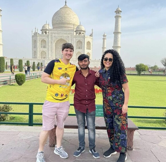 Three people posing in front of the Taj Mahal. 4