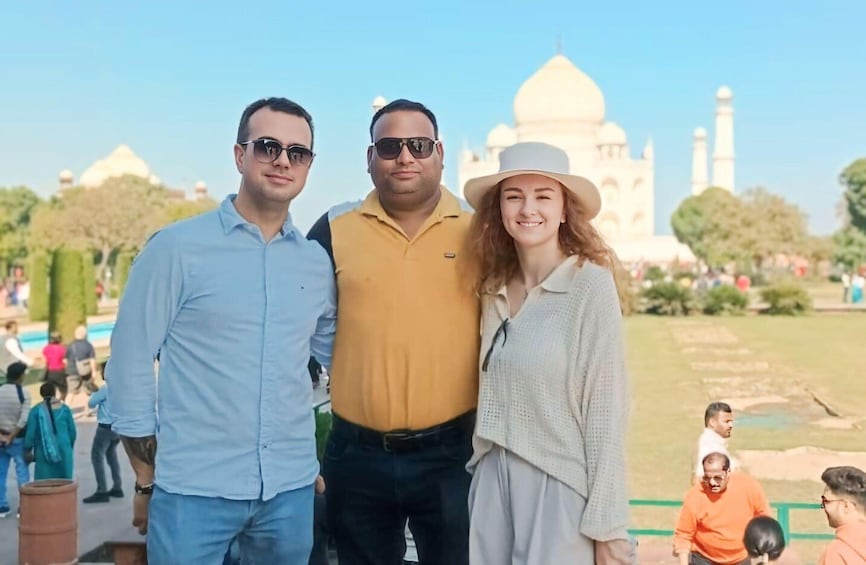 Three people standing in front of the Taj Mahal. 3