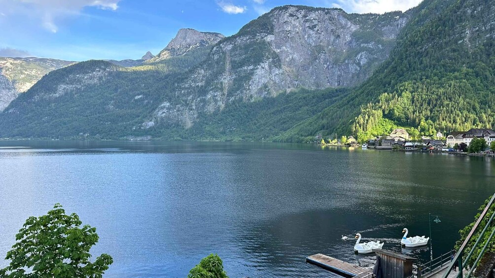 A calm lake surrounded by mountains, a dock with boats, and a small village. 4