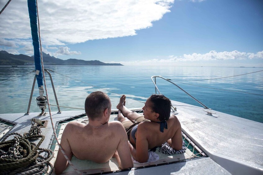 Two people sitting on a boat with a view of calm waters and distant mountains. 1
