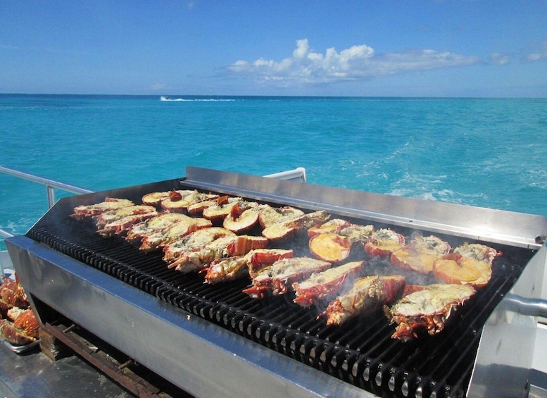 A grill with seafood and vegetables being cooked on a boat with a view of the ocean. 4