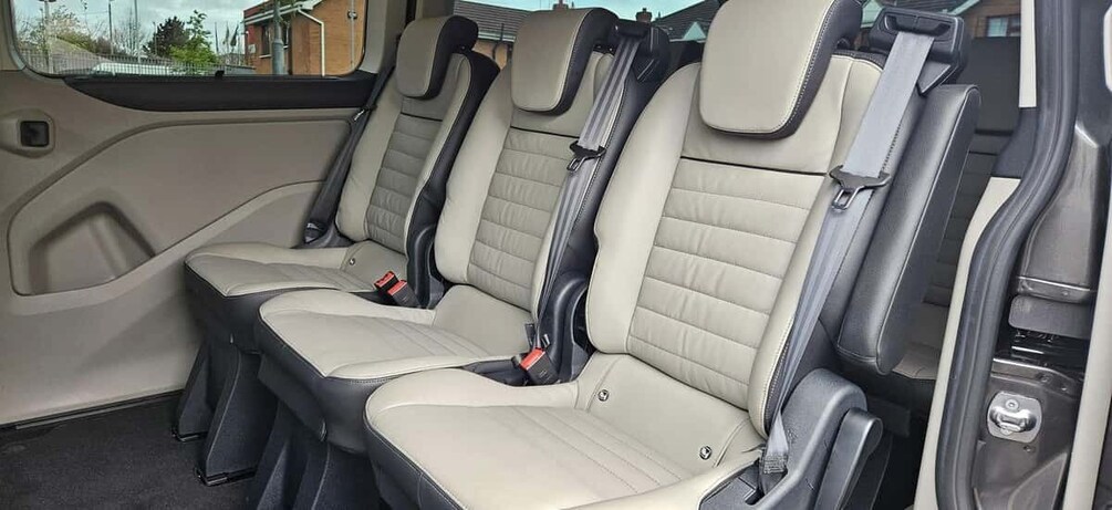 A car interior with beige leather seats and seat belts. 2
