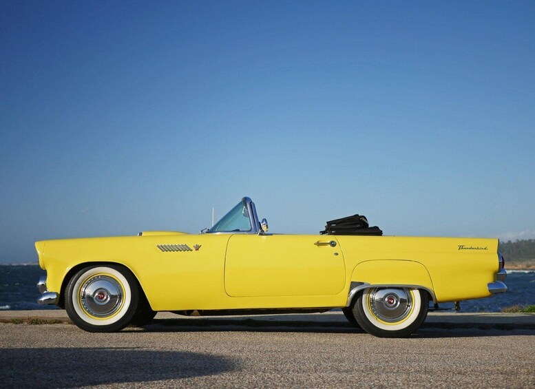 A yellow convertible car parked by the seaside. 2