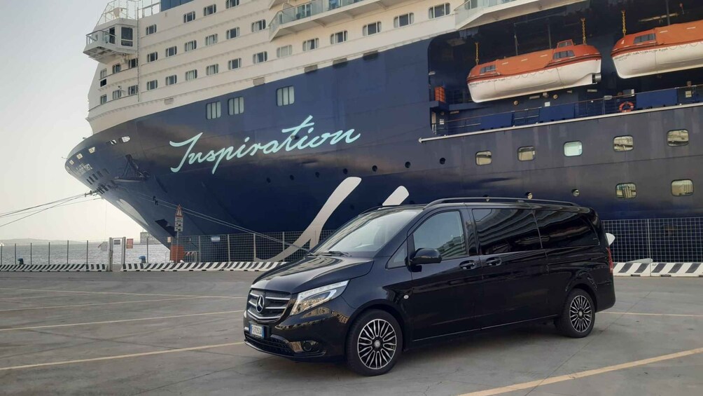 A black Mercedes-Benz car parked in front of a large cruise ship named 'Inspiration'. 1