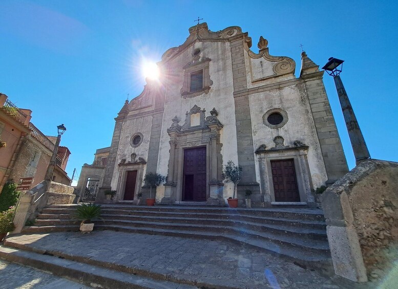 A historic church with ornate architecture, a large central door, and steps leading up to it. 2