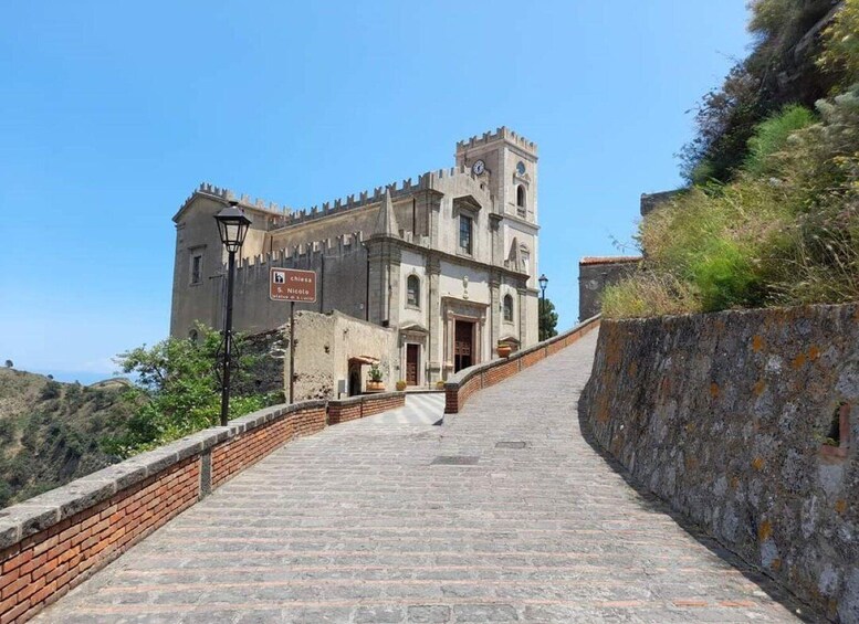 A historic building with a clock tower, a staircase leading up to it, and a sign indicating 'Chiesa S. Niccolo'. 3